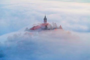 Die Leuchtenburg mit dem markanten Rundturm taucht nur schemenhaft aus einem Nebelfeld auf.