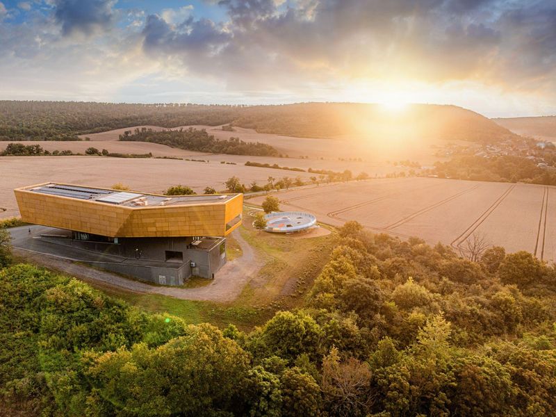 Die markante Kubatur und goldene Farbe des Besucherzentrums „Arche Nebra“ sind von der auf der Himmelsscheibe von Nebra dargestellten Sonnenbarke inspiriert. Foto: Saale-Unstrut Tourismus GmbH, Falko Matt