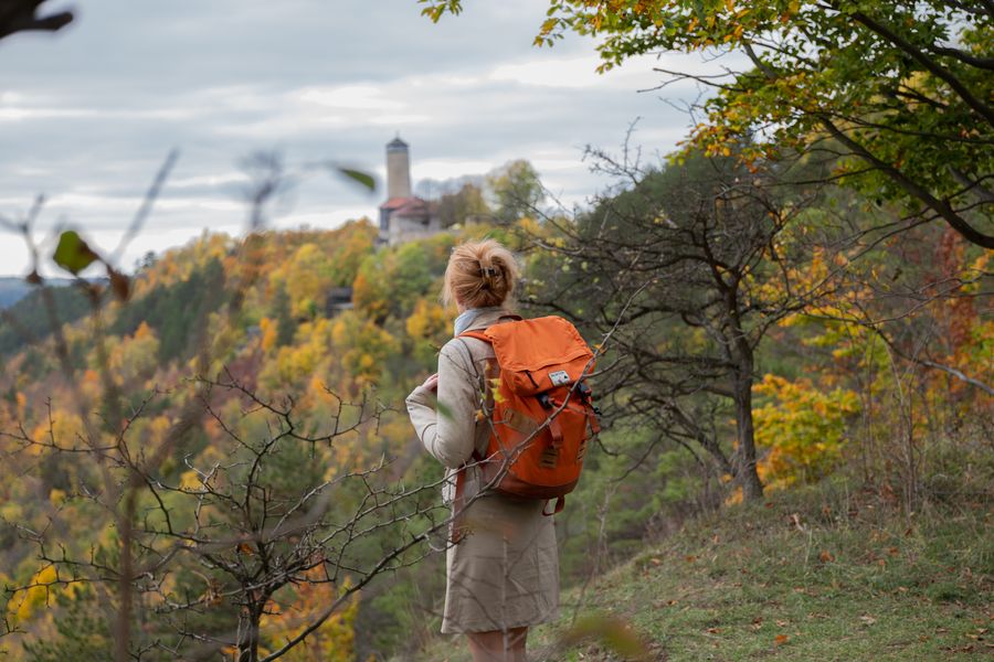 Unterwegs auf der SaaleHorizontale rund um die Universitätsstadt Jena: Der Qualitätsweg eröffnet immer wieder besondere Ausblicke, wie hier über die herbstlich gefärbten Wälder von Ziegenhain hinüber zum Fuchsturm, dem markanten Bergfried der ehemaligen Burg Kirchberg. Foto: Thüringer Tourismusverband Saale-Holzland e. V., Falko Matte