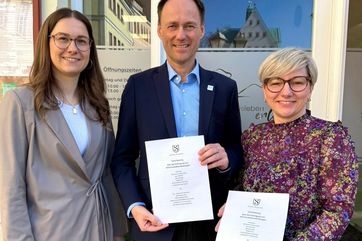 Louisa Mahrenholz, Ronny Strebeund Antje Peiser halten den unterzeichneten Kooperationsvertrag hoch